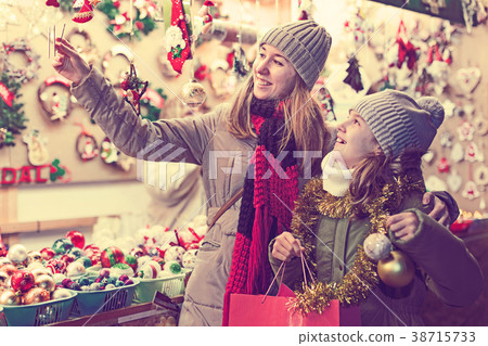 Smiling girl with woman are buying Christmas ornamentals Smiling girl with woman are buying Christmas ornamentals 38715733