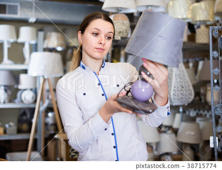 Girl is choosing modern table lamp in furniture store. 38715774