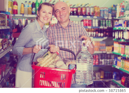 happy woman and man with shopping basket with bottle of water happy woman and man with shopping basket with bottle of water 38715865
