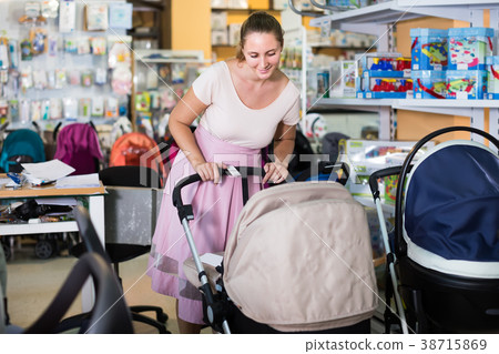satisfied pregnant woman looking for baby carriage at kids shop satisfied pregnant woman looking for baby carriage at kids shop 38715869