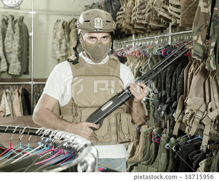 adult guy in military equipment with weapon in army shop adult guy in military equipment with weapon in army shop 38715956