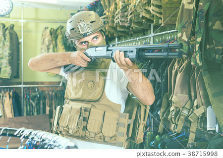 guy in military equipment with gun in airsoft shop guy in military equipment with gun in airsoft shop 38715998