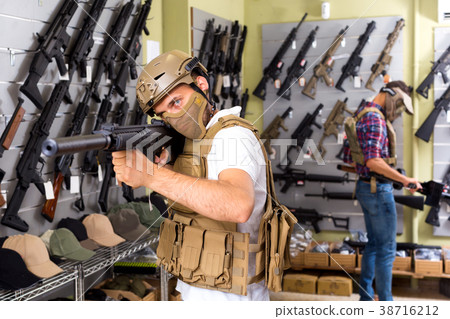 Male customers try on ammunition with weapon 38716212