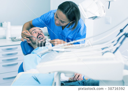 doctor woman in uniform is examinating of man on the chair in the dental office 38716392