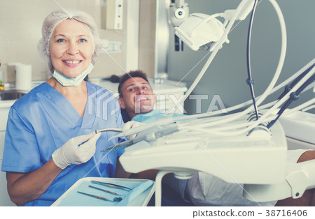 Female dentist with male patient in chair 38716406