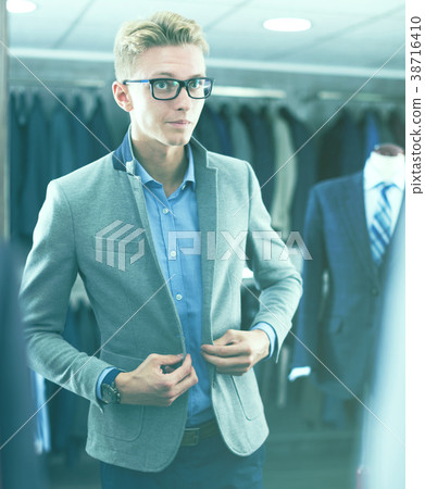 costumer in the glasses trying jacket in the shop 38716410
