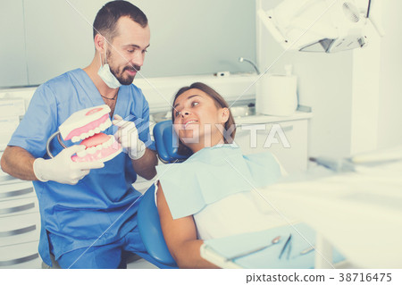 doctor in uniform is telling about hygiene of teeth in dental office doctor in uniform is telling about hygiene of teeth in dental office 38716475