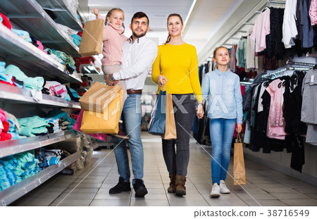 Young happy parents with two little girls shopping in mall, carrying purchases 38716549