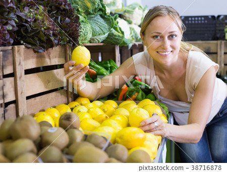woman holding lemons in hands in fruit store 38716878