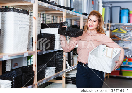 Woman choosing different plastic basket for storage in household shop Woman choosing different plastic basket for storage in household shop 38716945