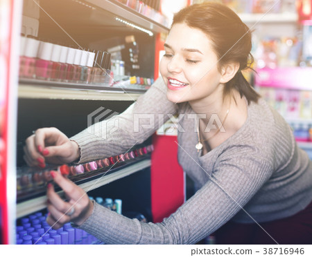 Smiling woman customer browsing rows of lipstick 38716946