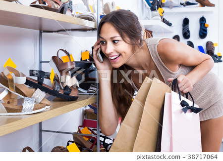 portrait of woman chatting on phone while picking new shoes in store portrait of woman chatting on phone while picking new shoes in store 38717064