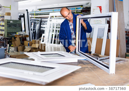 Man working in workshop for assembling plastic windows Man working in workshop for assembling plastic windows 38717360