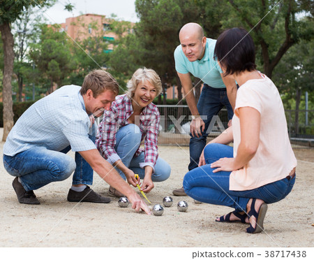 Cheerful males and females playing petanque Cheerful males and females playing petanque 38717438