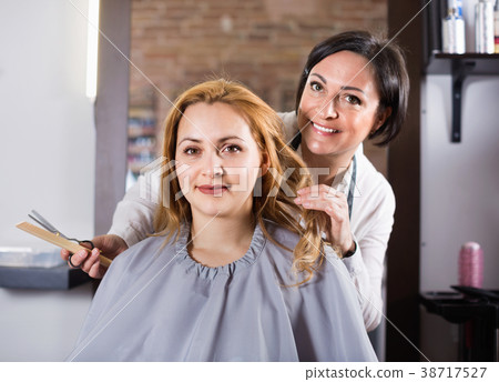 Woman very much likes her fashionable hairdress in hairdressing salon 38717527