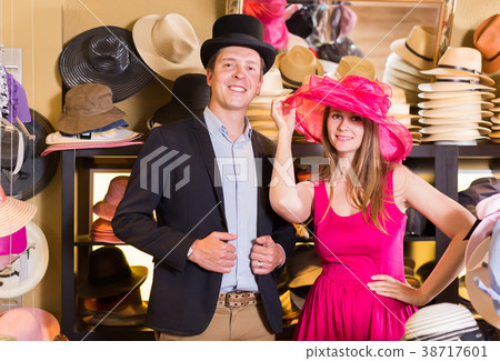 Glad woman and man trying on fashion hats 38717601