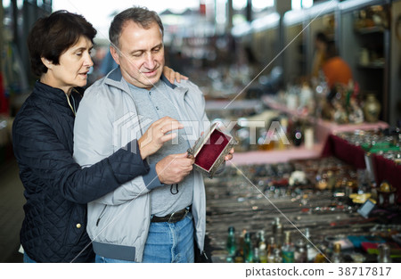 Adult man and woman are choosing jewelry box at the market of old things. Adult man and woman are choosing jewelry box at the market of old things. 38717817