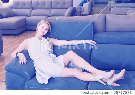 young female is testing sofa in furniture store 38717878