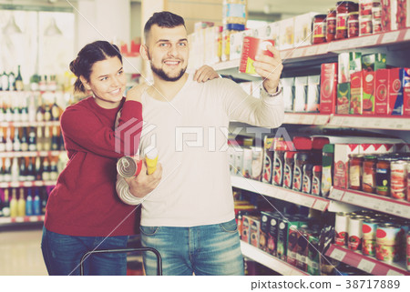 Happy couple choosing purchasing canned food for week at supermarket 38717889