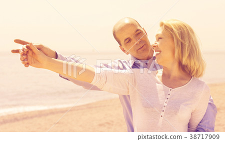 man showing something to his wife on the beach man showing something to his wife on the beach 38717909