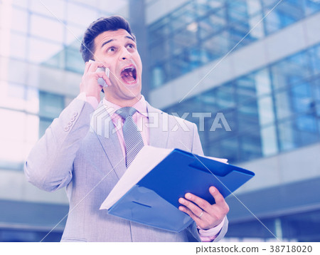 Surprised businessman with documents and phone Surprised businessman with documents and phone 38718020