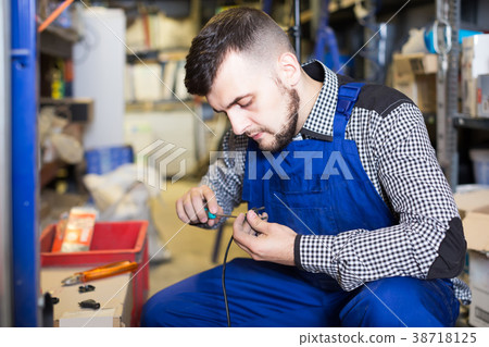 Worker repairs a plug with a screwdriver Worker repairs a plug with a screwdriver 38718125