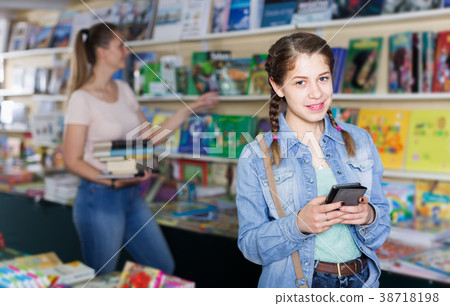 Portrait of emotional girl picking textbooks and talking on telephone Portrait of emotional girl picking textbooks and talking on telephone 38718198
