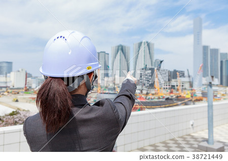 A woman in a suit wearing a helmet looks over the construction site A woman in a suit wearing a helmet looks over the construction site 38721449
