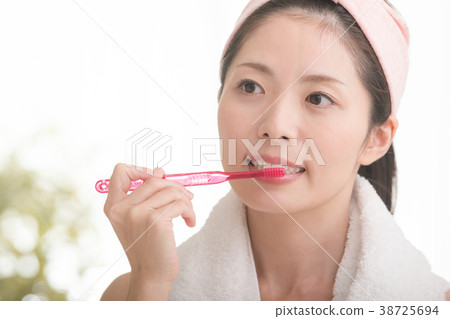 A young woman brushing her teeth A young woman brushing her teeth 38725694
