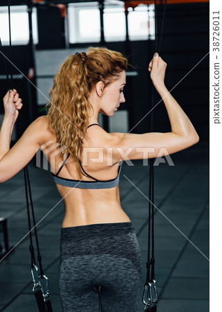 Crossfit woman standing with her back in the gym. Crossfit woman standing with her back in the gym. 38726011