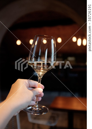 A glass of white wine in a woman's hand 38726191