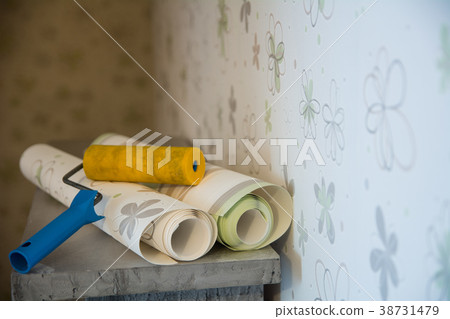 Two rolls of wallpaper and a roller lie against Two rolls of wallpaper and a roller lie against 38731479