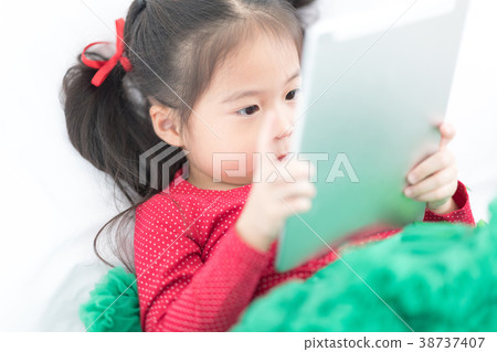 Cute Girl is Using Digital Tablet on Bed. Cute Girl is Using Digital Tablet on Bed. 38737407