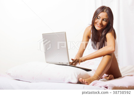 Young woman on bed using laptop Young woman on bed using laptop 38738592
