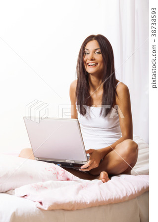 Young woman on bed using laptop Young woman on bed using laptop 38738593
