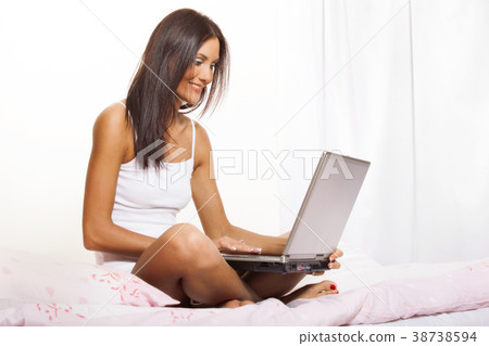Young woman on bed using laptop Young woman on bed using laptop 38738594