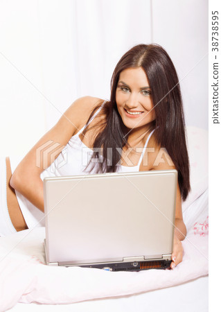 Young woman on bed using laptop Young woman on bed using laptop 38738595