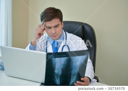 Smiling doctor posing in the office, he is wearing a stethoscope Smiling doctor posing in the office, he is wearing a stethoscope 38739370