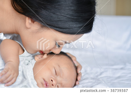 Newborn Concept. Mother and child on a white bed. Mom and baby b Newborn Concept. Mother and child on a white bed. Mom and baby b 38739387