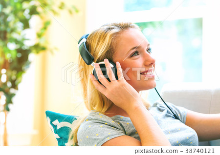 Happy young woman listening to music on headphones Happy young woman listening to music on headphones 38740121