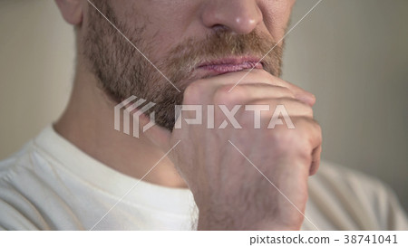Serious adult man with beard rubbing chin, having Serious adult man with beard rubbing chin, having 38741041