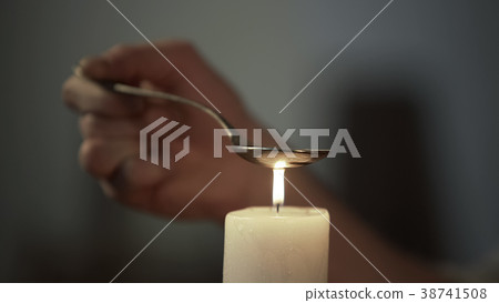 Hand of person heating chemical substance in spoon Hand of person heating chemical substance in spoon 38741508