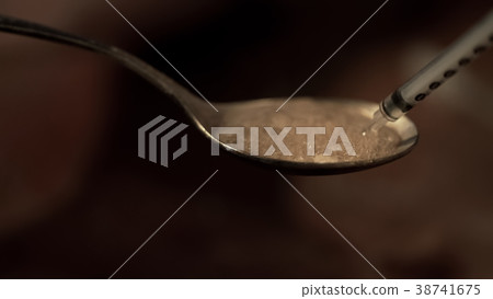 Syringe withdrawing heroin boiling on spoon Syringe withdrawing heroin boiling on spoon 38741675