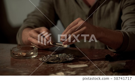Young man making cannabis cigarette to ease stress Young man making cannabis cigarette to ease stress 38741717