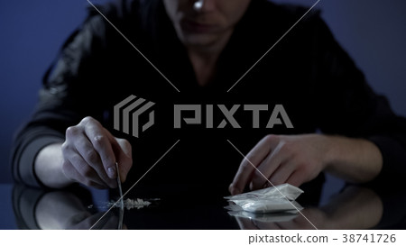 Young wealthy man forms cocaine lines on table Young wealthy man forms cocaine lines on table 38741726