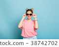 woman dressed in sunglasses on a blue background 38742702