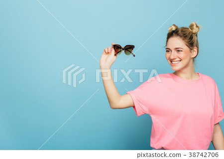 woman holding sunglasses on a blue background 38742706