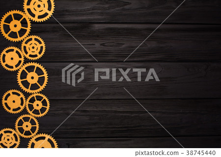 Border of gold gears on a black wooden background. View from above Border of gold gears on a black wooden background. View from above 38745440
