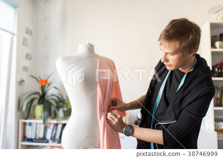 fashion designer with dummy making dress at studio 38746999