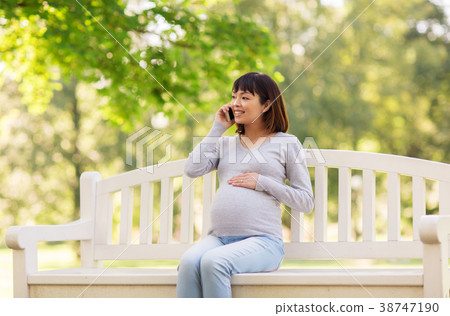 pregnant asian woman calling on smartphone at park 38747190